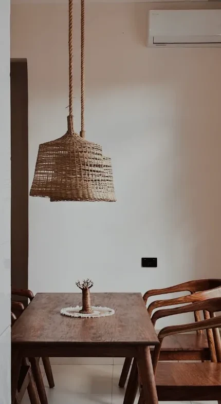 Long wooden dining table under a woven pendant lamp