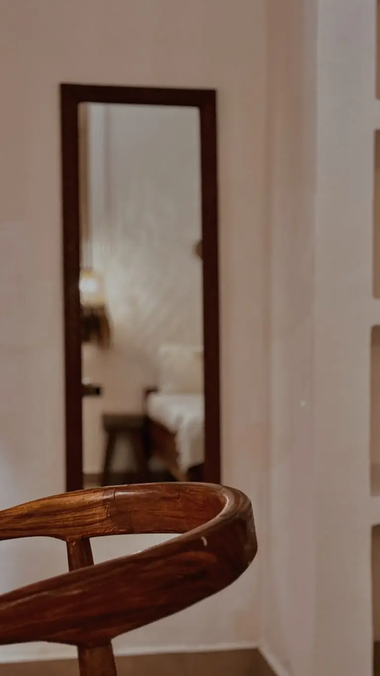 Tall mirror and wooden chair in a guest room